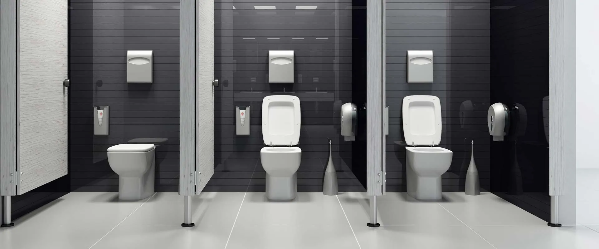 Commercial restroom with dividing partitions and white fixtures against a dark wall