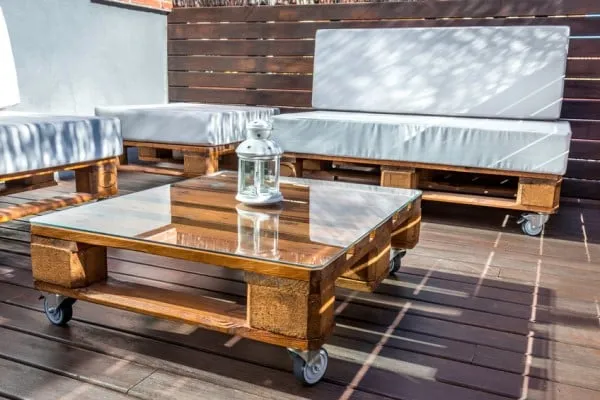 Wooden terrace lounge with a glass coffee table and light cushions