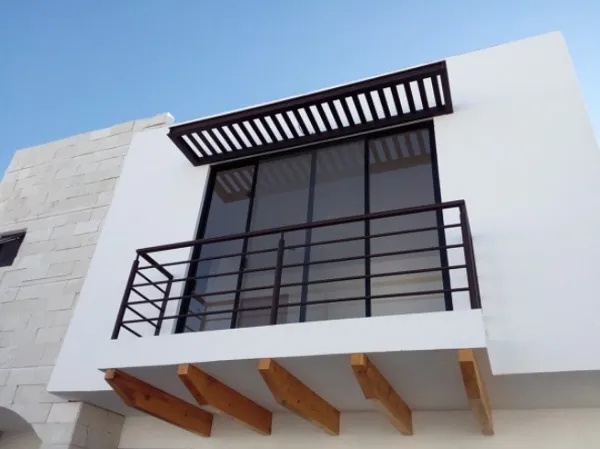Balcony with a dark steel railing, slatted sunshade and timber beams under the slab