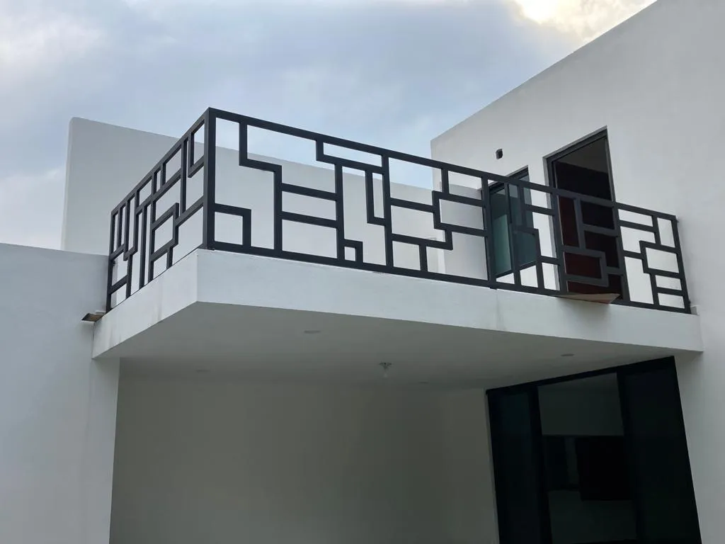 Black steel railing with a geometric pattern on the balcony of a white house